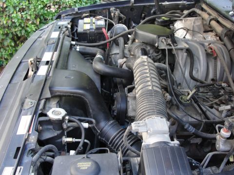 1967 Ford Mustang - Close-up view of an engine bay, showing various mechanical parts and wiring.
