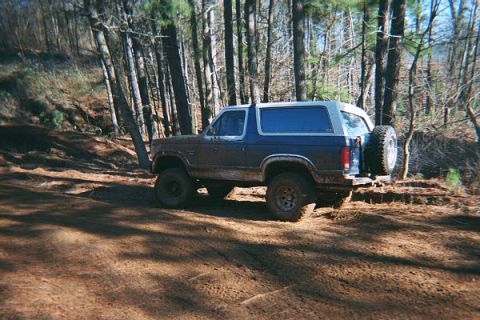 1986 Ford Bronco - This 1986 Ford Bronco is shown off-road, navigating a dirt path through a wooded area.