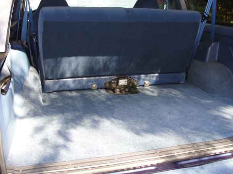1967 Ford Mustang - The interior cargo space of a vehicle, blue carpeting and a folded-down rear seat.