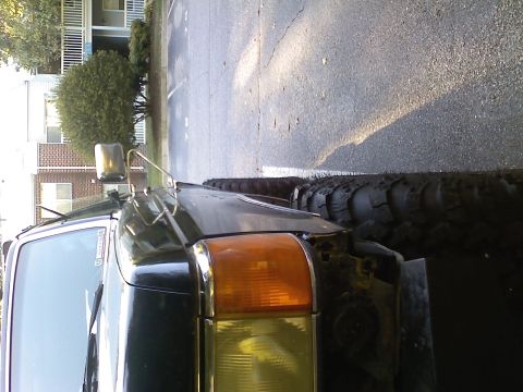 1990 Ford Bronco - Front corner view of a black SUV with prominent off-road tires and a chrome side mirror.