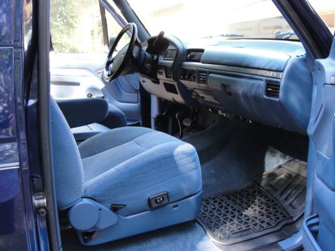 1967 Ford Mustang - The interior of a blue truck shows fabric seats and a dashboard with power seat controls.