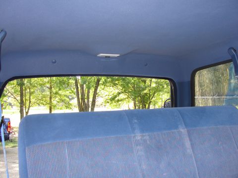 1967 Ford Mustang - Interior view of a vehicle's blue seat and headliner, with a glimpse of the outdoors through the rear window.