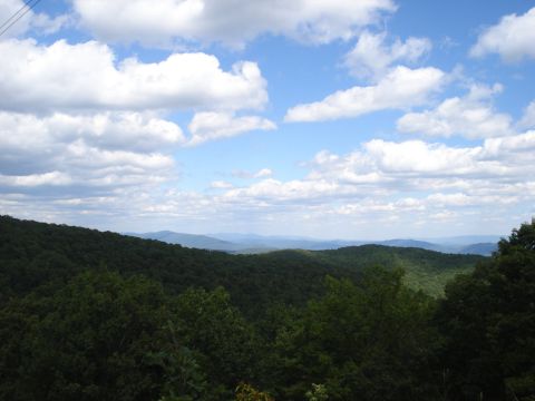 1992 Ford Bronco - A scenic view of rolling, tree-covered mountains under a cloudy blue sky.