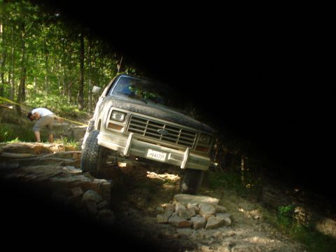 1992 Ford Bronco - Ford Bronco tackling an off-road trail with a person in the background.