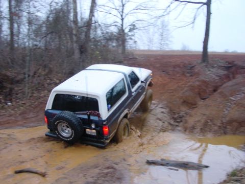 1986 Ford Bronco - Ford Bronco tackles a challenging muddy terrain during an off-road excursion.