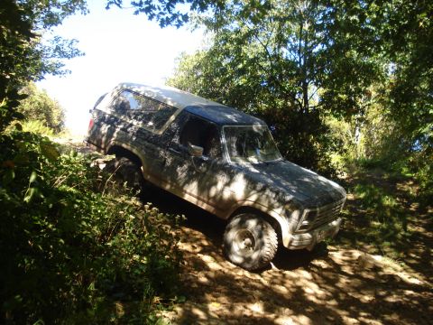1992 Ford Bronco - This SUV is navigating a challenging off-road trail, covered in mud from the journey.