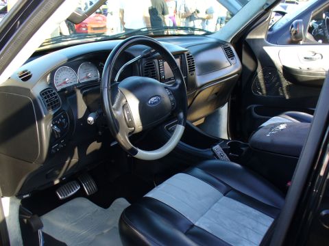 2007 Ford Mustang - The interior of a truck features a black and grey two-tone seat, a Ford steering wheel, and a dashboard with visible gauges and controls.