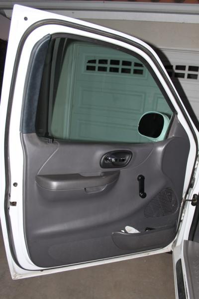 2007 Ford Mustang - The interior door panel of a white truck is shown, with a garage door visible in the background through the window.