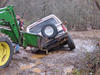 1986 Ford Bronco - A tractor assists a white SUV that has become stuck in muddy terrain.