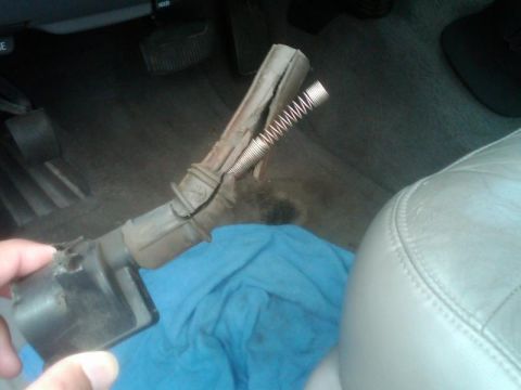 2007 Ford Mustang - A damaged steering column component is held up inside a car, with pedals visible in the background.