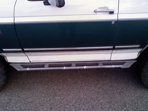 1996 Ford Bronco - Side view of a 1996 Ford Bronco, showing its two-tone paint and aftermarket step sliders.