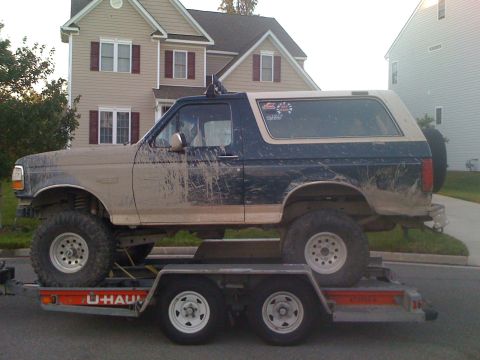 1992 Ford Bronco - A 1992 Ford Bronco, heavily coated in mud, is transported on a U-Haul trailer.