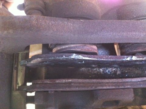 1997 Ford F-350 - Close-up view of a damaged and rusted brake caliper and rotor assembly, indicating potential brake problems.
