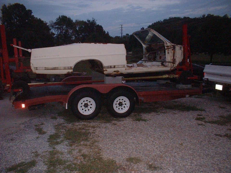 Car body being transported on a red trailer