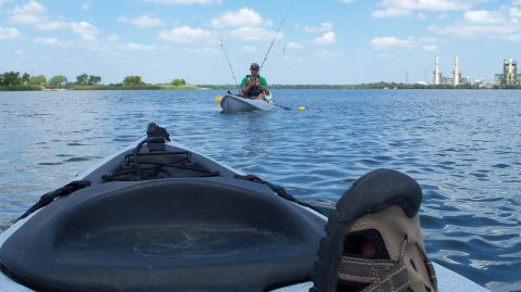 1953 Ford Mainline - Two kayaks are on a lake, with one fisherman casting a line in the distance under a partly cloudy sky.