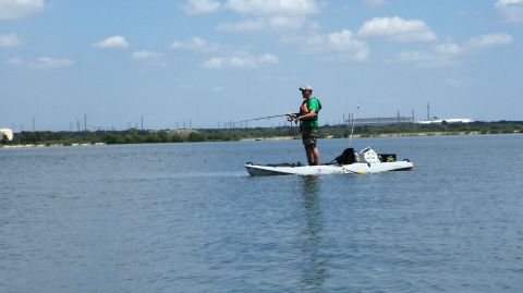 1953 Ford Mainline - A person enjoys a day of fishing while standing on a kayak in a calm body of water.