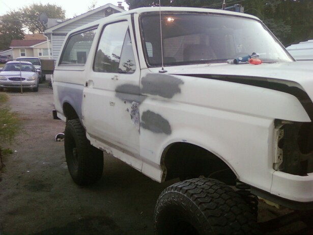 White 1989 Ford Bronco with body filler on fender and door