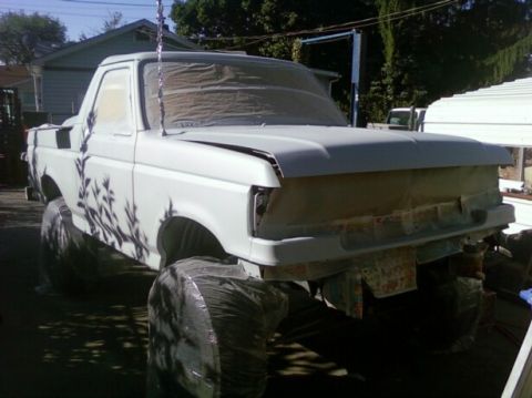 1989 Ford Bronco - A pickup truck, likely from the late 1980s, is covered in masking paper and plastic for bodywork.