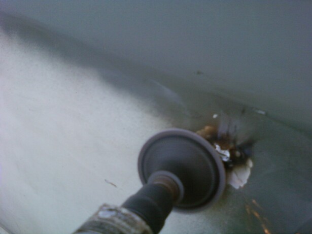Grinding wheel on a tool removing rust from a light-colored car body panel