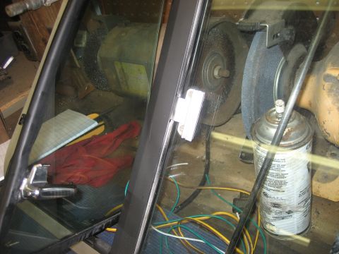 1978 Ford Bronco - View through a window shows a workbench with tools and supplies, including a bench grinder and spray can.