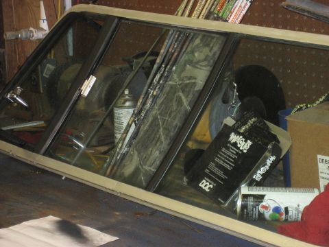 1978 Ford Bronco - A truck cap window frame with camouflage curtains is visible, along with various items on a workbench.