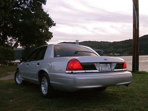 2000 Ford Crown Victoria - This silver 2000 Ford Crown Victoria is seen from the rear, parked on a grassy area near a body of water.