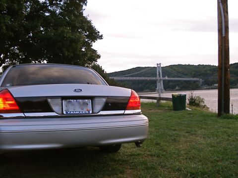 2000 Ford Crown Victoria - Rear view of a 2000 Ford Crown Victoria parked near a river with a bridge in the distance.