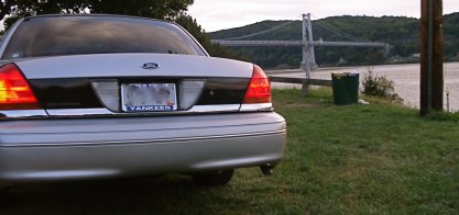 2000 Ford Crown Victoria - A silver 2000 Ford Crown Victoria is parked by a body of water with a bridge in the background.