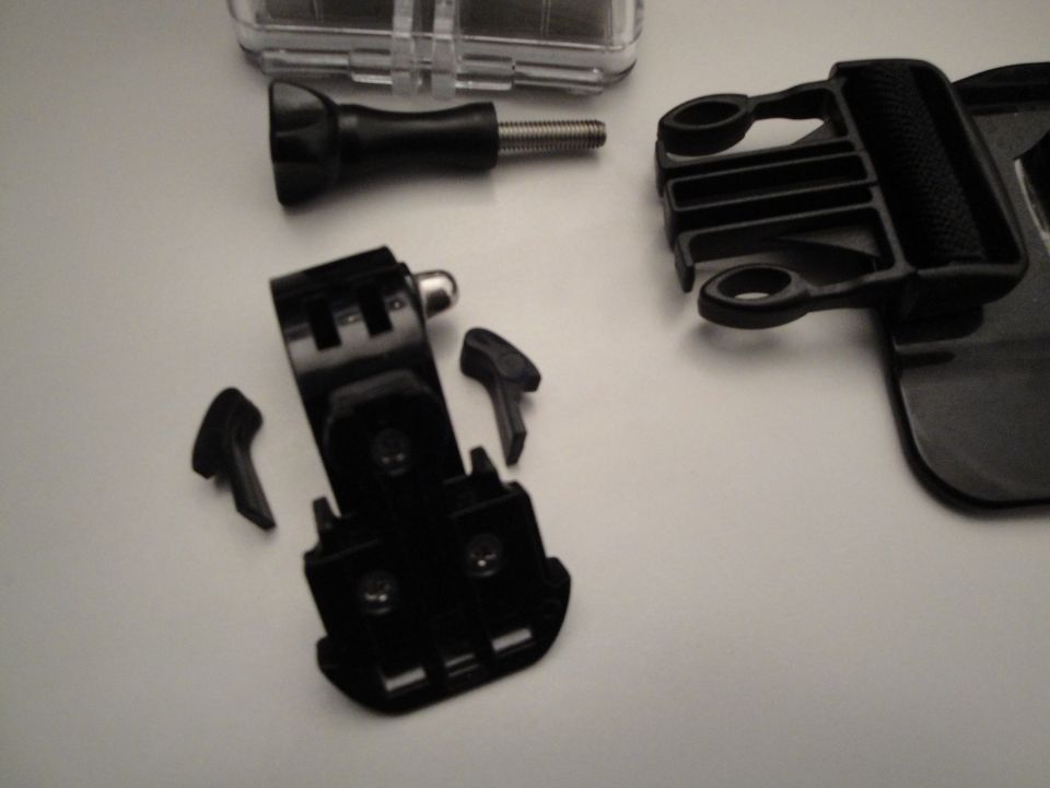 Camera mounting hardware, including a quick-release buckle and various adapters, laid out on a white surface