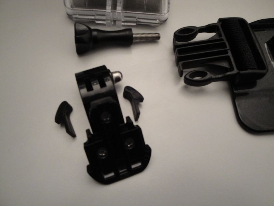 Camera mounting hardware and a clear plastic case on a white surface
