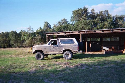 1986 Ford Bronco - This 1986 Ford Bronco is seen parked outdoors next to a rustic wooden shelter.