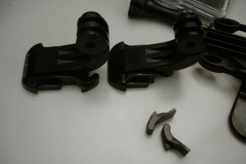 1993 Ford Taurus - Close-up of black GoPro camera mounts and small accessory parts on a white background.