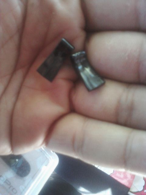 1993 Ford Taurus - Two small, dark, rectangular metal pieces are held in a person's palm.