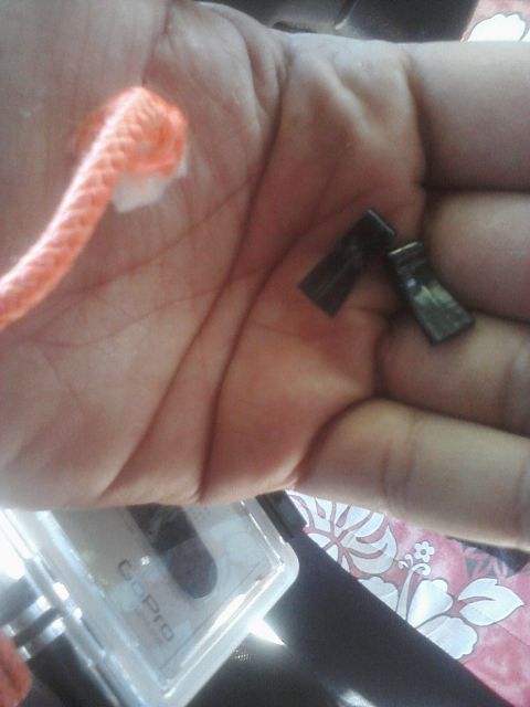 1993 Ford Taurus - A hand holds two small black clips and an orange cord, with a GoPro case visible below.