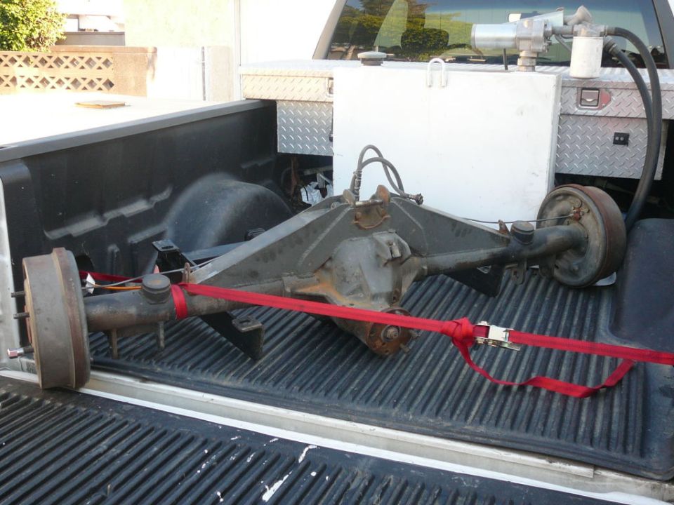 Rear axle assembly secured with red straps in a pickup truck bed