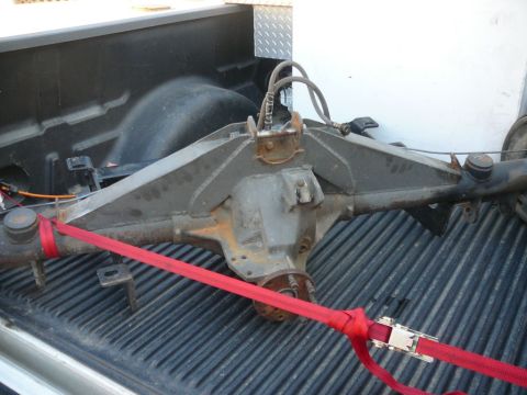 1988 Ford Bronco - A rear axle assembly is strapped down in the bed of a pickup truck.