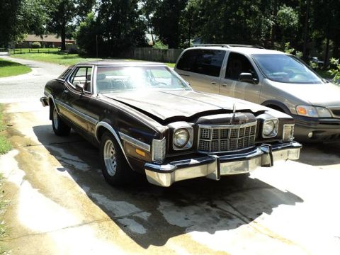 1974 Ford Elite - Brown 1974 Ford Elite coupe with hood slightly ajar, parked next to a tan minivan.