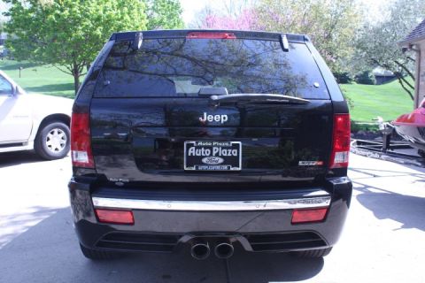 2008 Jeep Grand Wagoneer - Rear view of a black Jeep SUV with a license plate frame from Auto Plaza Ford, parked next to another vehicle.