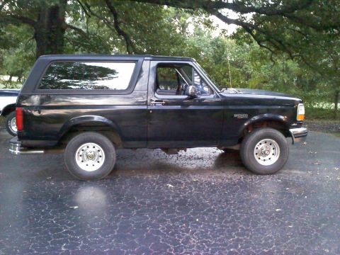 1995 Ford Bronco - Side view of a black 1995 Ford Bronco with tinted windows and aftermarket wheels.