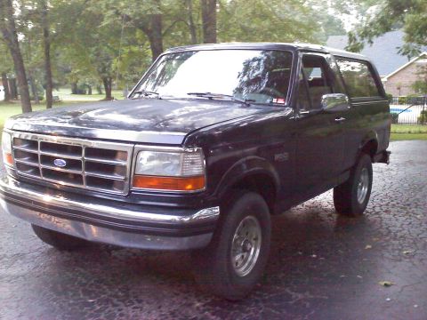 1995 Ford Bronco - This 1995 Ford Bronco is shown in a 3q-front view, parked on a paved surface with trees in the background.