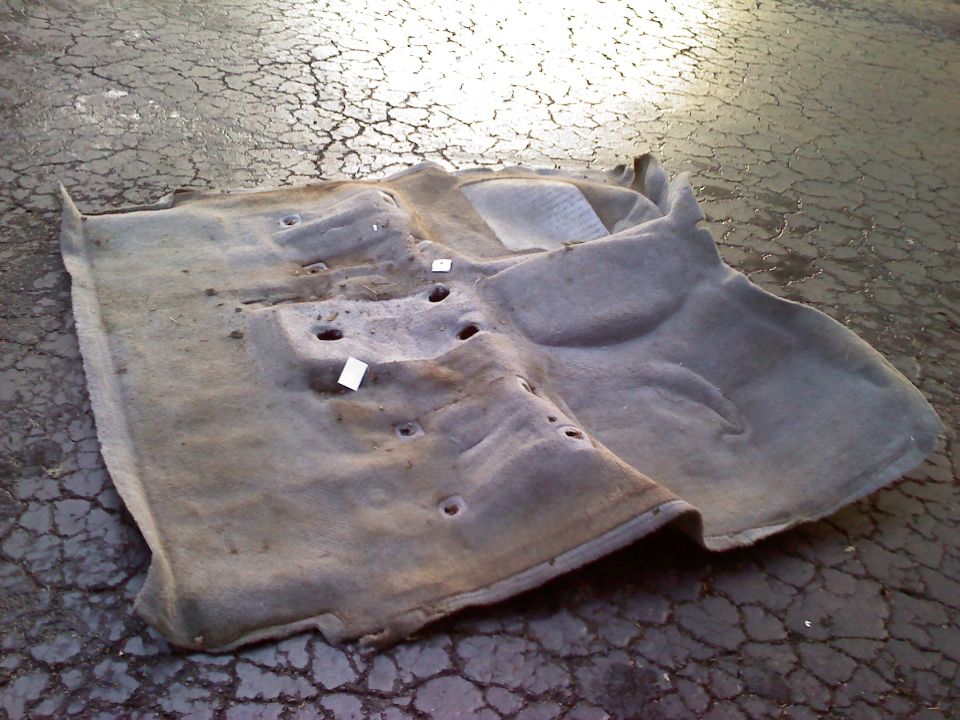 Carpet removed from vehicle, showing molded shape and mounting holes