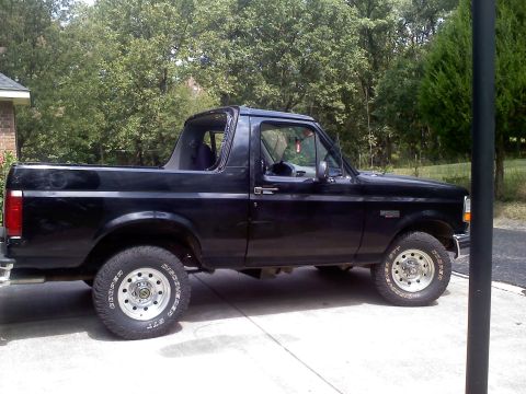 1995 Ford Bronco - Side profile of a black 1995 Ford Bronco with its top removed, parked on a paved surface.
