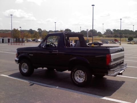 1995 Ford Bronco - The rear three-quarter view of a black Ford Bronco shows its removable top and chrome bumper.