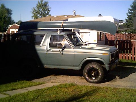 1981 Ford Bronco - This 1980s Ford Bronco is equipped for an outdoor adventure, carrying a canoe and towing a trailer.