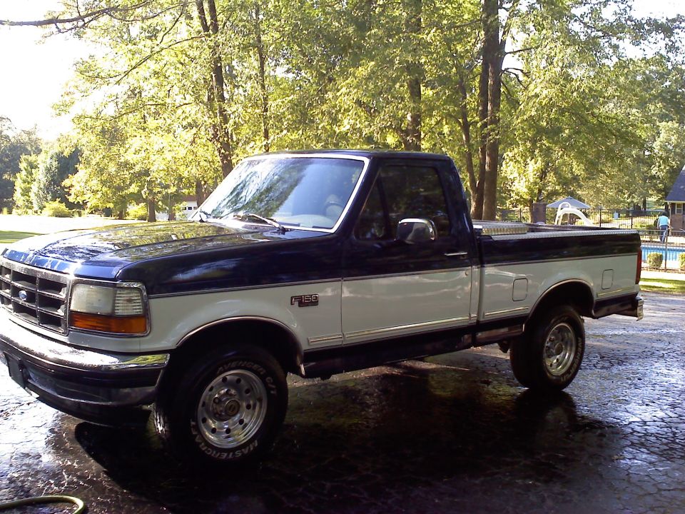 1995 Ford F-150 two-tone pickup truck parked on a wet driveway