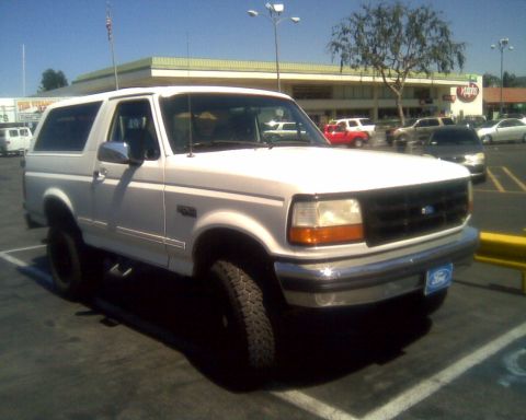 1994 Ford Bronco - White 1994 Ford Bronco parked in a lot under a blue sky.
