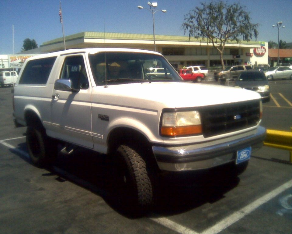 White two-door Ford Bronco with black grille and chrome bumper in a parking lot