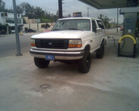 1994 Ford Bronco - A white Ford Bronco is parked at a gas pump, likely refueling.