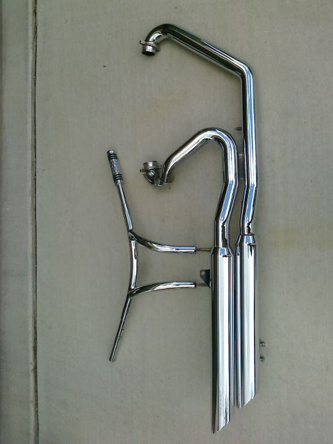 1997 Ford Probe - Chrome exhaust pipes and header for a motorcycle are laid out on a flat surface.