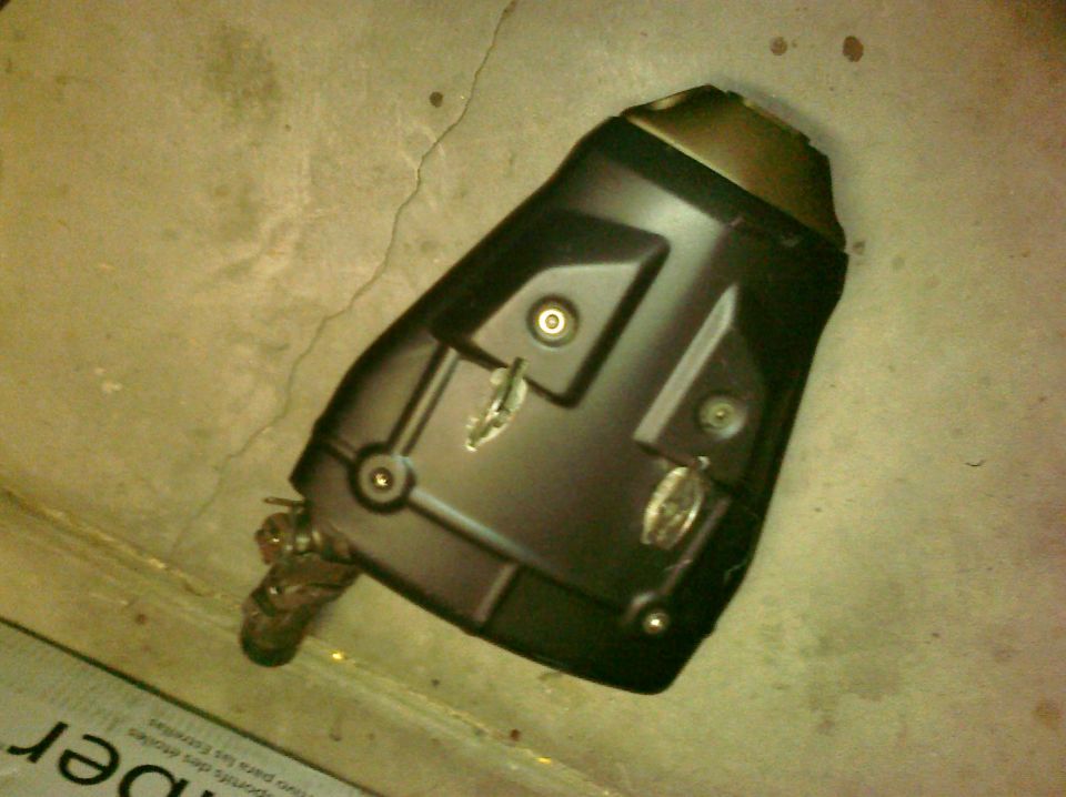 Motorcycle exhaust muffler on concrete floor. Supermotors.net logo visible